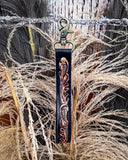 Decorative leather key fob with metal clasp on a natural background