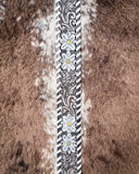 Decorative purse strap with floral pattern on a cow hide