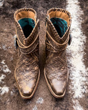 Pair of brown leather boots with intricate designs on a textured surface