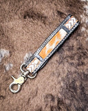 Decorative leather keychain with braided design on a textured surface