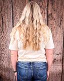 A girl wearing the Tough Luck Cowboy Graphic Tee, turned around to face the wall to show the back of the shirt.