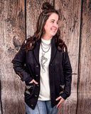 A woman wearing the Stand by Me Knit Sweater with one hand in her pocket, the other on her leg while looking to her left and smiling. She is standing in front of a wood back drop.
