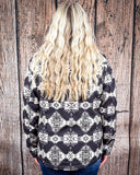 A girl wearing the Aztec City Soft Shell Jacket. She is facing the wall behind her to show the back of the jacket. 