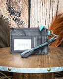 The back of the Prickly Pears Card Holder in Turquoise, showing the card slots. It is sitting on a wooden table with wheat and a wood back drop behind it.