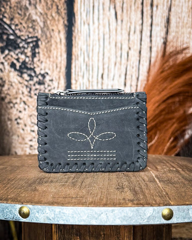 The Outlander Edge Credit Card Holder in Ash Grey displayed on a wooden table with wheat behind it. Sitting in front of a wood back drop.