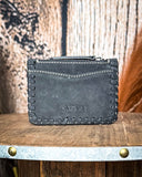 The back of the Outlander Edge Credit Card Holder in Ash Grey, displayed on a wooden table with wheat behind it with a wood back drop.