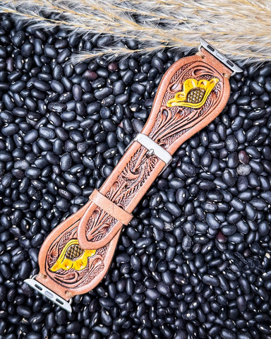 The Lone Star Hand Tooled Leather Watch Band in Antique Tan displayed on beans and wheat.