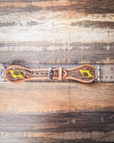 The Lone Star Hand Tooled Leather Watch Band in Antique Tan sitting on a ruler to show size, displayed on a wooden table.