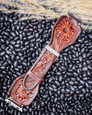 The Lone Star Hand Tooled Leather Watch Band in Antique Mahogany displayed on beans and wheat.
