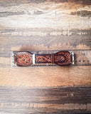 The Lone Star Hand Tooled Leather Watch Band in Antique Mahogany sitting on a ruler to show size, displayed on a wooden table.
