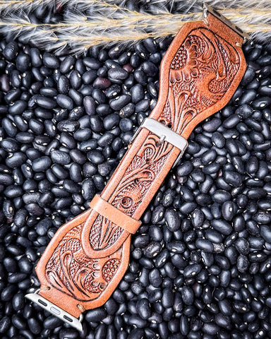The Lone Star Hand Tooled Leather Watch Band in Antique Saddle Brown displayed on beans and wheat.