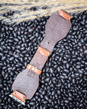 The back of the Lone Star Hand Tooled Leather Watch Band in Antique Saddle Brown displayed on beans and wheat.