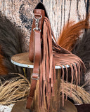 Side view of the Loralei Hair on Hide Fringe Crossbody Bag, being displayed on a wooden table with wheat behind it. It is in front of a wood back drop.