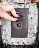Zoom in of the clasp on the Reveena Hair on Hide Fringe Phone Crossbody Bag, there are 3 slits at the top with 3 fingers opening the slits.