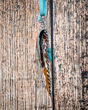 Side view of the Lark Hair on Hide Phone Crossbody Bag, hanging from a hook. There is a wood backdrop behind it.