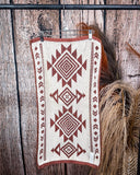 The back of the Myna Mesa Towel, clipped to a hanger that is hanging from a metal rod with wheat behind it in a wood back ground.