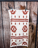The Terra Sands Towel, clipped to a hanger that is hanging from a metal rod with wheat behind it in a wood back ground.
