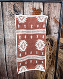 The back of the Terra Sands Towel, clipped to a metal rod with wheat behind it in a wood back ground.