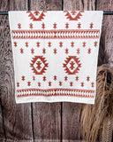 The Terra Sands face towel draped over a metal rod with wheat behind it in a wood back ground.