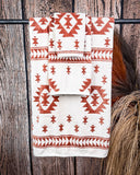 The Terra Sands Towel set hanging from a metal rod with wheat behind it in a wooden back ground.