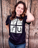 A girl modeling the Four Aces Graphic Tee in a wood back ground.