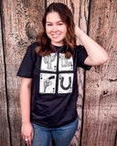 A girl modeling the Four Aces Graphic Tee in a wood back ground.