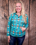 A model wearing the Laramie Kreek Fitted Pullover with her hand in her pocket, the other resting on her leg in a wood back ground.