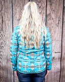 The model turned around, facing the wood panel to show the back of the Laramie Kreek Fitted Pullover.