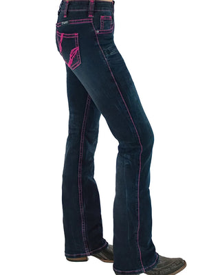 A side profile view of a person wearing dark blue flare jeans with bright pink contrast stitching and a pink embroidered logo on the back pocket, paired with brown boots against a white background.