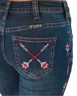 Close-up of the back of dark blue denim jeans worn by a model, featuring a black 'TUFF' brand patch on the back pocket and red-and-white embroidered crossed arrows on the pocket.
