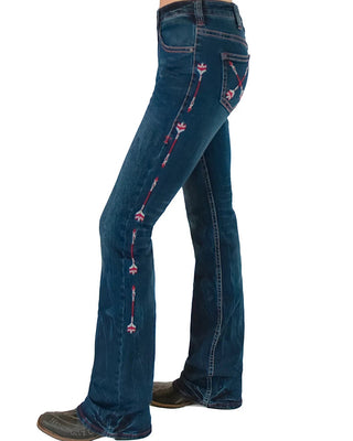Side view of a person wearing dark blue western flare jeans with pink embroidered floral details running down the outer seams, paired with dark boots against a white background.