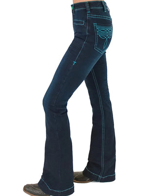 A side profile view of a person wearing dark blue flare jeans with bright turquoise contrast stitching and decorative stitching on the back pocket, paired with brown boots against a white background.