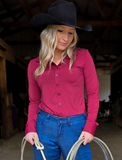 A cowgirl wearing the Garnet Grit Pullover Button Up inside of a barn.