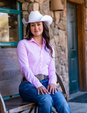 Cowgirl sitting on a bench wearing the Sugar and Cinch Pullover Button Up in front of a building. 