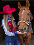 Model wearing the  Stars Stripes and Rodeo Nights Pullover next to a horse.