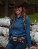 Model posing in front of logs wearing the Saddle Stitch Pullover Button Up.