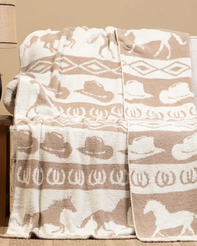 Beige and white western patterned blanket draped over a chair with a lamp on a side table.
