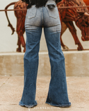 Person wearing blue flared jeans with a decorative bull sculpture in the background