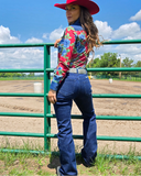 Woman in a colorful shirt and red hat standing in a fenced area with a blue sky.