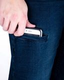 Hand placing a smartphone into a pocket of dark blue jeans on a white background