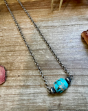 Necklace with a turquoise bead on a wooden surface
