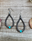 Pair of beaded earrings with turquoise beads on a wooden surface