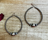 Pair of beaded hoop earrings on a wooden surface
