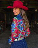 Woman wearing a red floral blouse and cowboy hat in a barn setting