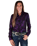 Woman wearing a purple patterned shirt and jeans with a studded belt on a white background