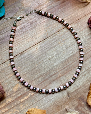 Necklace with pink and silver beads on a wooden surface