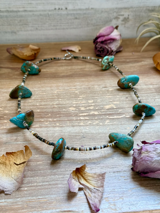 Necklace with turquoise beads on a wooden surface with dried flowers