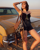Woman posing in front of a vintage car in a desert setting