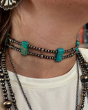 Close-up of a person wearing multiple necklaces with turquoise accents.