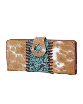 A western-style bifold wallet featuring a tan and white cowhide pattern, a turquoise and brown embroidered center panel, and a snap-button closure with a turquoise stone.